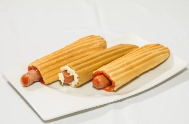 Çöreğin içinde sosis. Sosisli sandviçi beyaz tabakta hazırla.