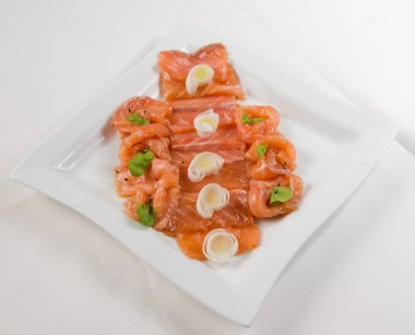 Beyaz bir tabakta yumurta ve bitkilerle kırmızı balık fileto dilimleri..