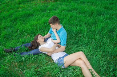 Kız yeşil çimlerin arasındaki adamın dizlerinin üzerinde yatıyor..