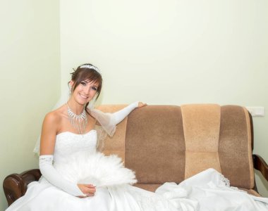 Beyaz elbiseli gelin kanepede oturuyor..