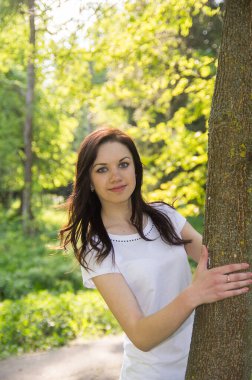 Baharın arka planında genç bir kızın portresi. Güneş lekeli taze yeşillik. Yumuşak seçici odak.