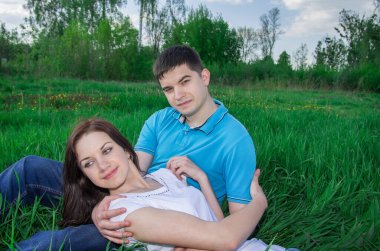 Kız yeşil çimlerin arasındaki adamın dizlerinin üzerinde yatıyor..