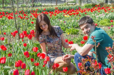 Bahçede çiçek açan kırmızı lalelerin arasında sevgi dolu bir çift..