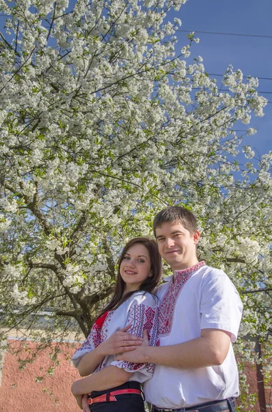 Młoda Kochająca Para Mężczyzna Kobieta Białych Haftowanych Koszulach Pobliżu Kwitnącego — Zdjęcie stockowe