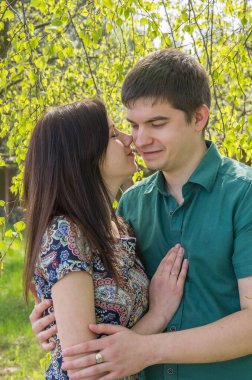 A couple in love, a man and a woman among the branches of a birch with young spring green leaves.