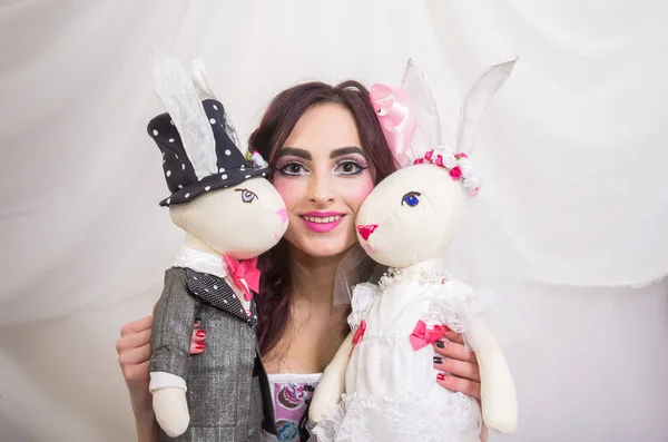人形のように見える明るく暗い髪の少女がウサギの人形で遊んでいます バイオレットの色合い 白い背景 — ストック写真