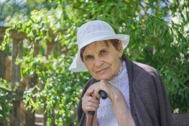 Beyaz panama giymiş yaşlı bir kadının portresi yeşil bir arka planda..