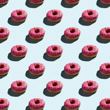 Pembe donutların pürüzsüz desenleri, gölgeli sıcak bir arka planda.