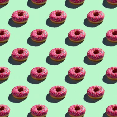 Pembe donutların pürüzsüz desenleri, gölgeli sıcak bir arka planda.