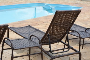 Güverte koltuğu. Brezilya, Güney Amerika 'da bir eko-turizm çiftliğinde arka planda havuz ve panoramik fotoğrafta hasırdan yapılmış bir sandalye.