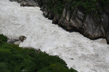 Vahşi ve devasa su akıntısı, Kaplan Sıçrayan Geçit oluşumunu temsil eden büyük kayanın etrafından geçiyor.
