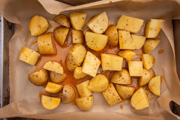 Gesnipperde verse aardappelen in kleine stukjes en besprenkeld met olie en specerijen om Amerikaanse aardappelen te bereiden door bakken in de oven — Stockfoto