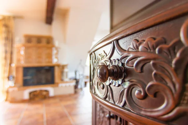 Wood carving commode drawer and beige ceramic tiled stove in the old style in background — Stock Photo, Image