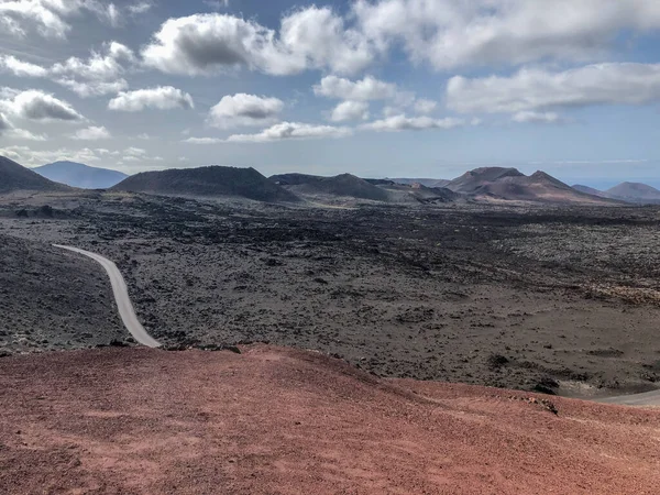 A volcanic landscape and road at Timanfaya national park with vulcans and montains on the background, at Lanzarote, Canary islands. Spain.