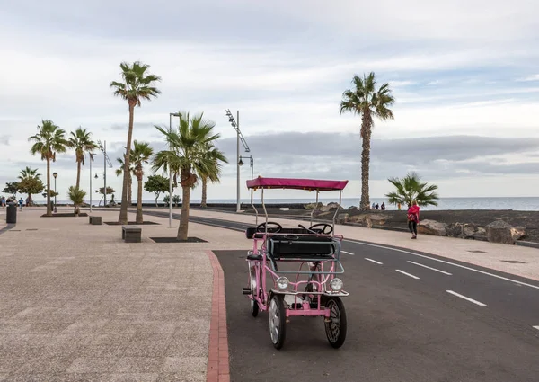 Aile bisikleti gezinti güvertesinde arka planda Lanzarote, Kanarya Adaları 'nda bir plaj manzarası var.