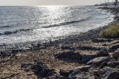 Karanlık kum ve kayalarla kaplı volkanik plaj ve Playa de Matagorda, Lanzarote, Kanarya Adaları, İspanya 'da rüzgara karşı bir barınak.