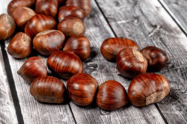 biraz çiğ kestane, kestane (Castanea sativa), açık renkli ahşap kırsal arka plan üzerine seçici odaklı klasik bir sonbahar meyvesi..
