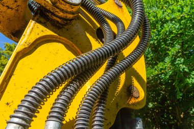 Kazıcı kovasına güç aktarımı için bir tekerlek yükleyicisinin kova kolundaki hidrolik hortumlar.