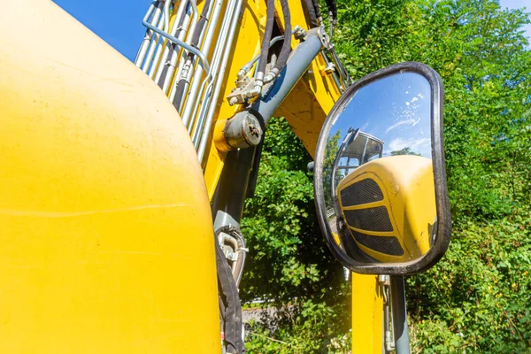 yellow gray wheel loader with excavator shovel. Reflection over exterior mirror