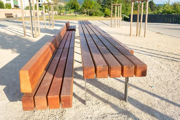 long wooden bench and solid wooden table in a public area of a new development to increase the quality of stay