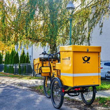 Berlin, Almanya - 23 Ekim 2021: Berlin 'in kenar mahallelerindeki bir sokakta bulunan Deutsche Post şirketinden elektrikli bisiklet.