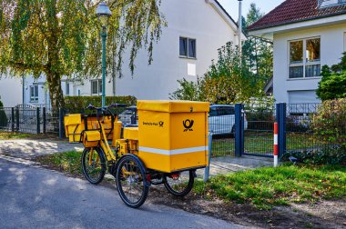 Berlin, Almanya - 23 Ekim 2021: Berlin 'in kenar mahallelerindeki bir sokakta bulunan Deutsche Post şirketinden elektrikli bisiklet.