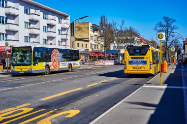 Berlin, Almanya - 22 Mart 2022: Berlin, Almanya 'nın varoşlarındaki Lichtenrade' da küçük bir alışveriş caddesinde bir otobüs durağında sokak sahnesi.