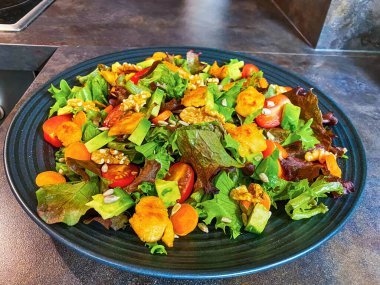 Marul, domates, havuç, ceviz ve vejetaryen kümes hayvanlarından yapılmış taze salata tabağı..