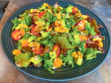 Marul, domates, havuç ve cevizden yapılmış taze salata tabağı..