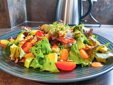 Marul, domates, havuç ve cevizden yapılmış taze salata tabağı..