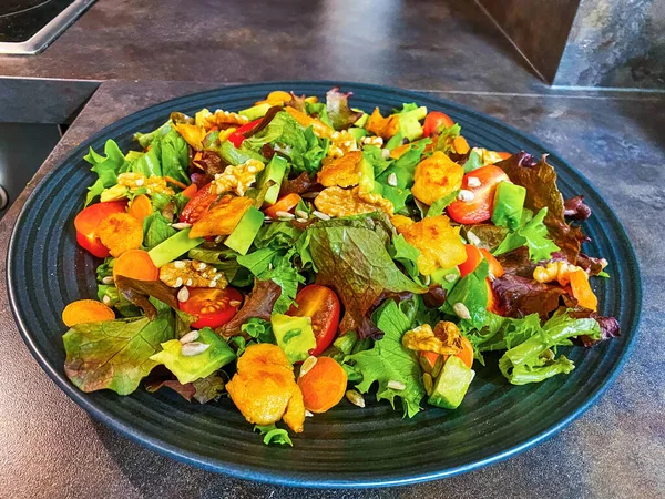 Marul, domates, havuç, ceviz ve vejetaryen kümes hayvanlarından yapılmış taze salata tabağı..