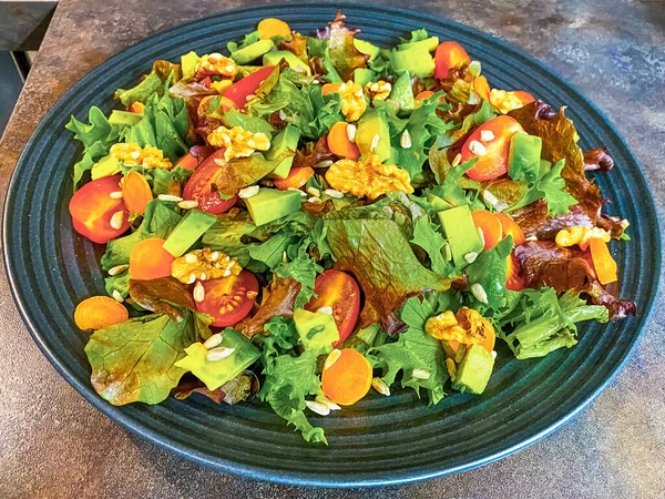 Marul, domates, havuç ve cevizden yapılmış taze salata tabağı..