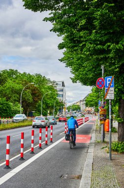 Berlin, Almanya - 29 Mayıs 2022: Yol güvenliğini artırmak için ana yolda özel bir bisiklet şeridinde bisikletçi.