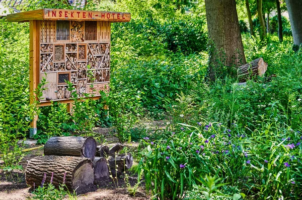 View to an insect hotel made of different materials to offer a retreat for many species. The text above is German for insect hotel.