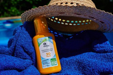 Berlin, Germany - July 24, 2022: Anti-sunburn spray on a blue towel by a swimming pool.