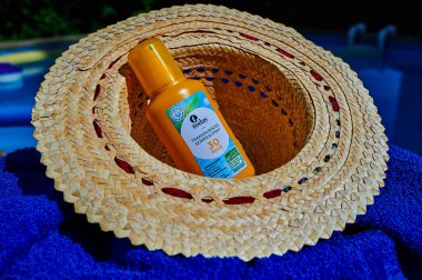 Berlin, Germany - July 24, 2022: Anti-sunburn spray on a blue towel by a swimming pool.
