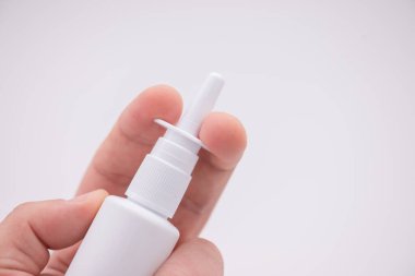 Beyaz arka planda izole edilmiş parmaklar arasında burun spreyi tutmak