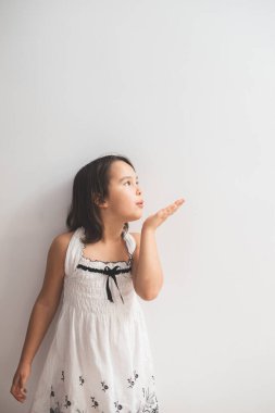 Beyaz bir duvarın yanında duran ve öpücükler saçan tatlı kız.