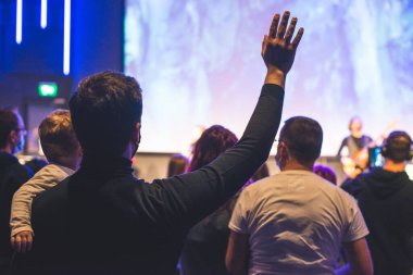 Kollarında çocuğu olan ve kilisede Tanrı 'ya şükreden bir adamın elleri havada.