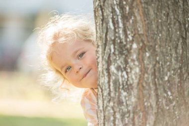 Cute little boy with curly blonde hair play hide and seek