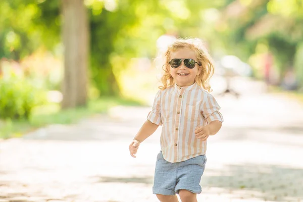 可愛いです男の子とともに巻きブロンド髪遊びで公園 — ストック写真