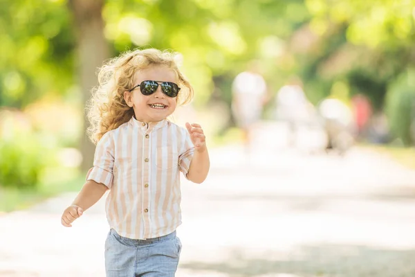 可愛いです男の子とともに巻きブロンド髪遊びで公園 — ストック写真