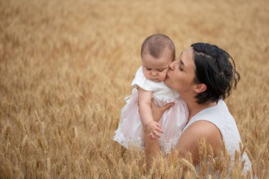 Mutlu anne ve güzel kızı buğday arka planında.