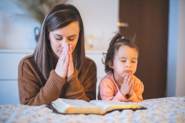 Anne ve küçük kızı sabahları yatağın kenarında dua ediyorlar.