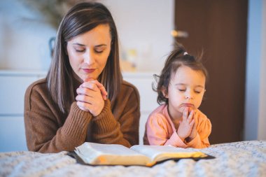Anne ve küçük kızı sabahları yatağın kenarında dua ediyorlar.