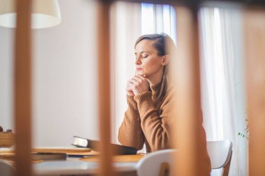 Sabahları masada okuyan ve dua eden bir kadın.