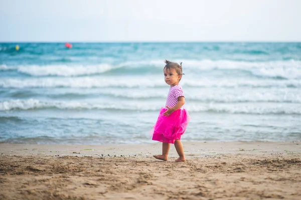 海滩上穿着粉色衣服的可爱小女孩的画像 — 图库照片