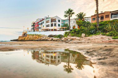 Güzel beyaz evler, Akdeniz ve batan güneşin altında açık mavi bir gökyüzü ve El Roc de Sant Gaieta, Katalonya 'da gün batımı