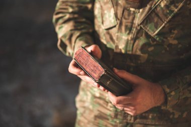 Elinde İncil 'le kamuflaj üniforması giymiş bir asker. Askerler Tanrı 'nın sözlerini okuyup meditasyon yapıyorlar.
