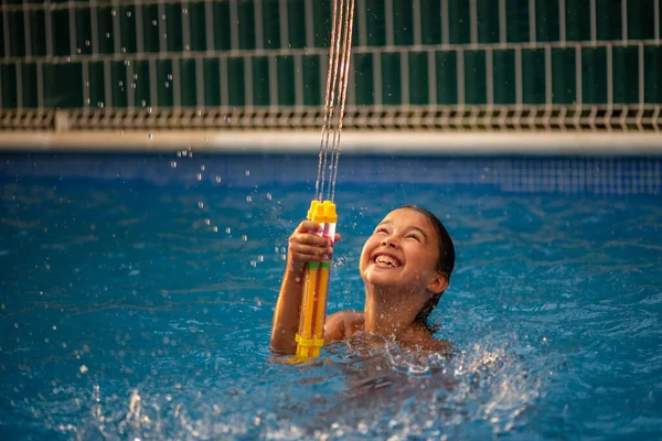 小女孩玩水枪和在游泳池里游泳很开心 — 图库照片